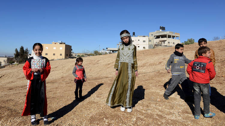 Palestinian girls in traditional clothes stand on a field cleared of land mines in the West Bank village of Husan, near Bethlehem, last December.