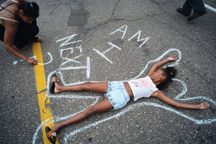 In this July 7, 2016 photo, Tia Williams and her daughter Aissa create a display on the street outside the Minnesota governor's official residence in St. Paul, Minn., as people gathered to protest the shooting death of Philando Castile by police (Richard Tsong-Taatarii/Star Tribune via AP)/Star Tribune via AP).
