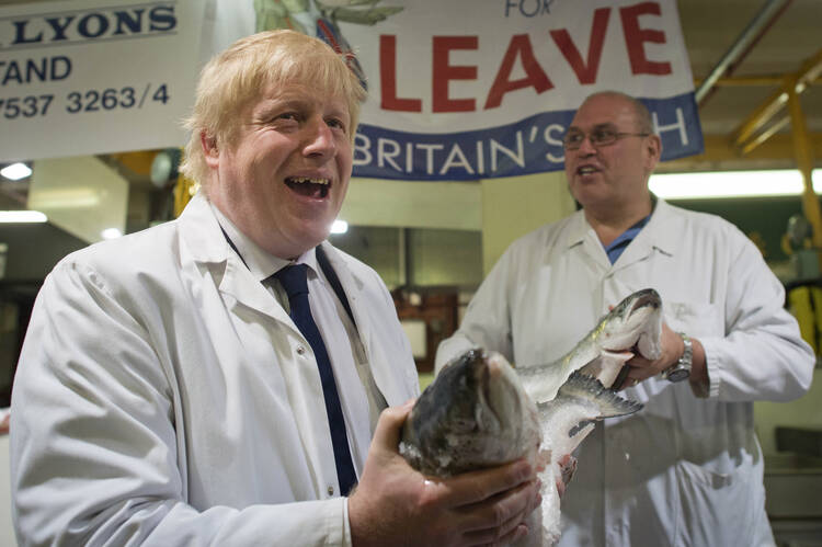 British MP Boris Johnson, left, holds a wild salmon standing next to with porter Greg Essex at Billingsgate Fish Market in London, Wednesday June 22, 2016 on the final day of campaigning before Thursday's EU Referendum. (Stefan Rousseau/PA via AP) 