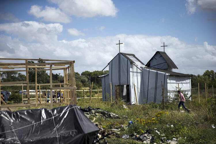 A migrant walks past a makeshift church in the "Jungle" camp in France (CNS photo/Etienne Laurent, EPA).