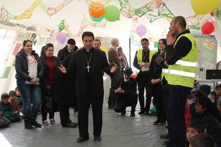 Bishop Oscar Cantu of Las Cruces, N.M., chats with displaced Yezidi children Jan. 20 outside of Dohuk during a recent visit to the Kurdistan region of Iraq. (CNS photo/Dale Gavlak)