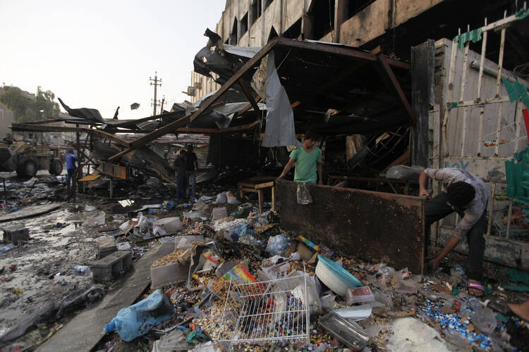 People gather at the site of an Oct. 2 car bomb attack that killed 11 people in Baghdad. (CNS photo/Ahmed Saad, Reuters)
