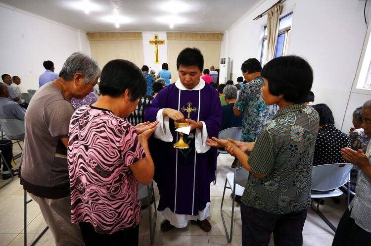 Father Liu Yong Wang distributes Communion during Mass in a makeshift Catholic chapel in a village outside Tianjin, China, July 17, 2012.