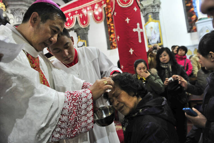 Chinese Catholic priests baptize new believers during a 2013 Easter Vigil in a church in Shenyang, China. A papal visit to China does not appear likely anytime soon, according to experts on the church in China. (CNS photo/EPA)