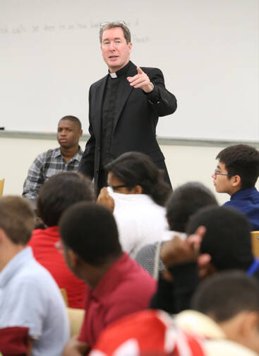 Jesuit Father James Van Dyke, principal of Cristo Rey Atlanta Jesuit High School, addresses students during an orientation, August 2014.