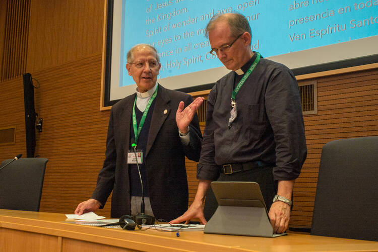 Father Adolfo Nicolas, the outgoing Jesuit superior, hands over the meeting to Jesuit Father Jim Grummer during an Oct. 3 gathering in Rome to elect a new superior general. (CNS photo/Don Doll, S.J.) 