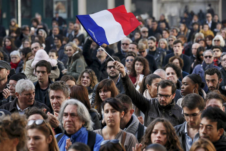A man waves a French flag as several hundred people gather to observe a minute of silence in Lyon, France, Nov. 16 (CNS photo/Robert Pratta). 