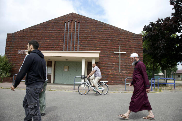 People walk past St. Therese Church in Saint-Etienne-du-Rouvray, France, near Rouen July 27, a day after a French priest was killed with a knife during Mass (CNS photo/Pascal Rossignol, Reuters).