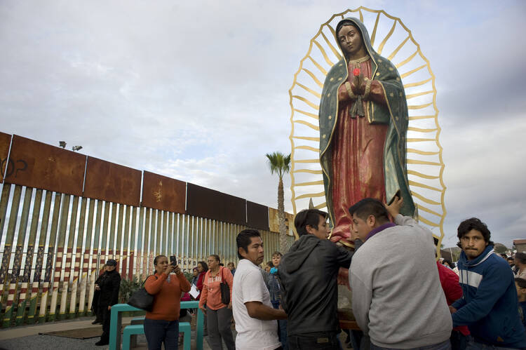 A statue of Our Lady of Guadalupe is unloaded from a truck after a Nov. 19 procession to the U.S.-Mexico border fence in Tijuana, Mexico, where Mass was celebrated (CNS photo/David Maung).