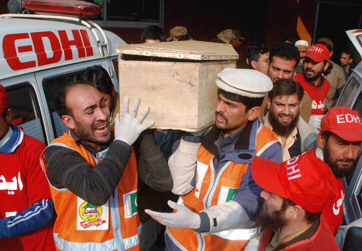 Rescue workers and family members carry the coffin of a student killed during a Dec. 16 attack by Taliban gunmen on the Army Public School in Peshawar, Pakistan. (CNS photo/Khuram Parvez, Reuters)