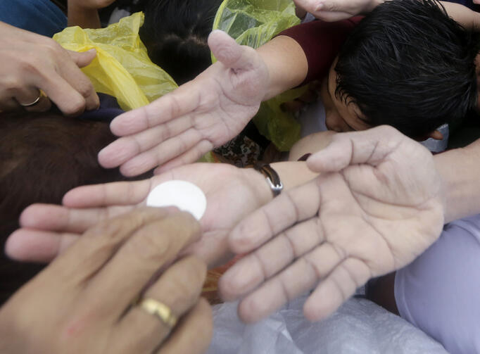 Pilgrims reach to receive Communion as Pope Francis celebrates Mass Jan. 18 in Manila, Philippines (CNS photo/Francis Maalasig, EPA).