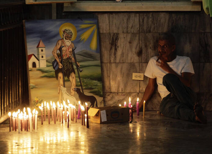 A worshipper smokes a cigar beside a painting in the shrine of St. Lazarus in the town of El Rincon, Cuba, in December 2013. (CNS photo/Desmond Boylan, Reuters)