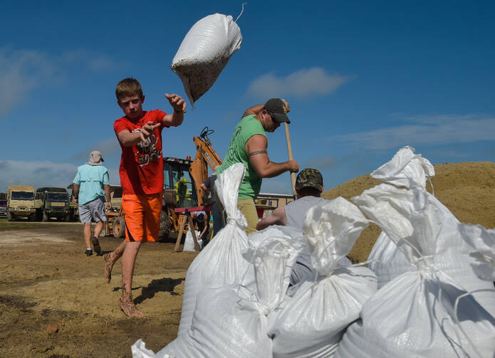Dylan Heinan, among other volunteers, piles sandbags in an effort to stop flood waters from rising in Lake Arthur, La., Wednesday, Aug. 17, 2016. (Scott Clause/The Daily Advertiser via AP)