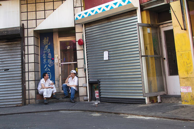 GOOD CONVERSATION. Two men take a smoke break in Old Chinatown in Manhattan.