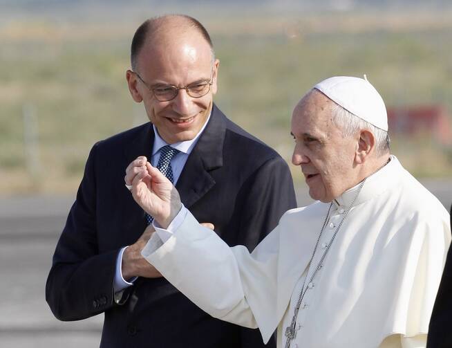 Pope Francis talks with Italy’s Prime Minister Enrico Letta before boarding a plane at Fiumicino airport in Rome in July 2013 to join more than 300,000 young people for World Youth Day in Brazil. (CNS photo/Giampiero Spo sito, Reuters