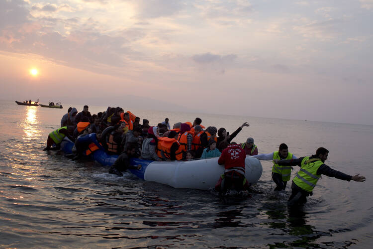 In this Sunday, March 20, 2016 file photo, volunteers help migrants and refugees on a dingy as they arrive at the shore of the northeastern Greek island of Lesbos, after crossing the Aegean sea from Turkey. (AP Photo/Petros Giannakouris, File)