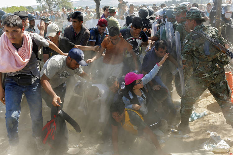 Migrants scuffle with police after breaking through a fence Sept. 2 and crossing the border between Macedonia and Greece, near the town of Gevgelija, Macedonia. (CNS photo/Valdrin Xhemaj, EPA)