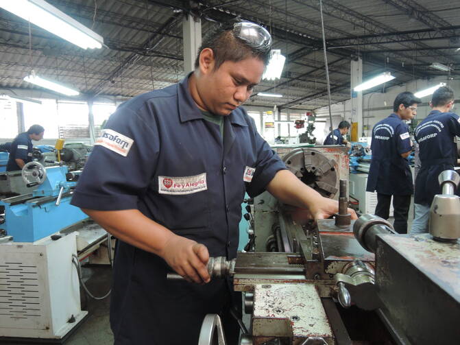 A metalworking student uses a lathe at a Fe y Alegria training center in San Salvador. The Jesuit educational organization uses training to improve the lives of young men and that might otherwise emigrate.