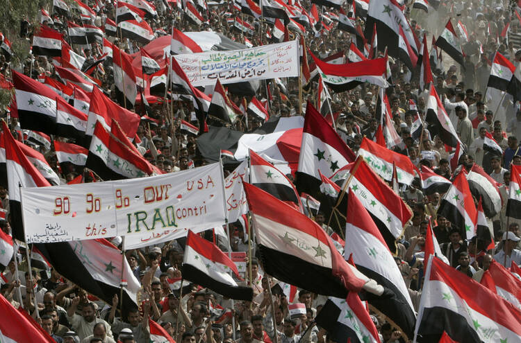 Protesters hold Iraqi flags as they march during an April 9 anti-U.S. protest called by Shiite Muslim cleric Muqtada al-Sadr in Najaf, Iraq, to mark the fourth anniversary of the fall of Baghdad in 2003. (CNS photo/Ceerwan Aziz, Reuters)