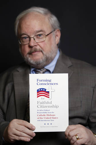 John Carr, former executive director of the U.S. bishops' Department of Justice, Peace and Human Development, is pictured Feb. 28, 2012 holding "Forming Consciences for Faithful Citizenship." 