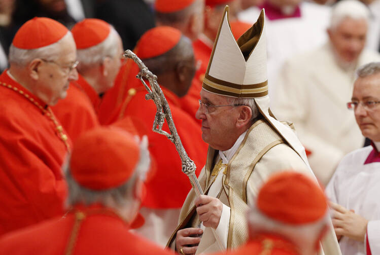 Pope Francis leaves after a consistory at which he created 20 new cardinals in St. Peter's Basilica at the Vatican Feb. 14. Retired Pope Benedict XVI, pictured at right in the background, attended the ceremony. (CNS photo/Paul Haring)