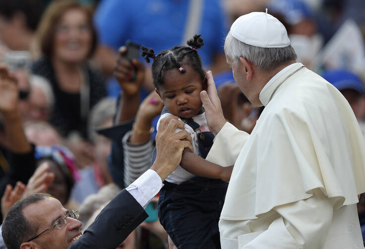 Pope Francis greets a child as he arrives to lead his general audience in St. Peter's Square at the Vatican Sept. 17. (CNS photo/Paul Haring)