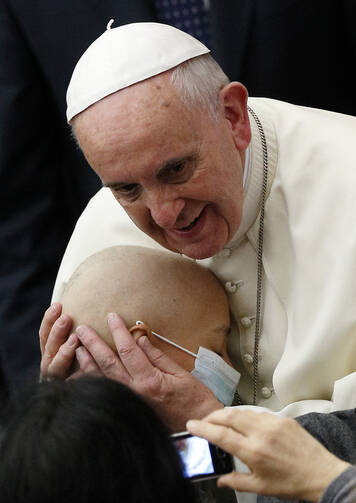 Pope Francis embraces a sick child during an audience with accountants in Paul VI hall at the Vatican Nov. 14. (CNS photo/Paul Haring)