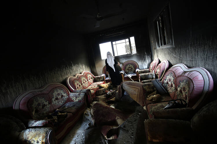 A Palestinian woman inspects a damaged house in Gaza City, Aug. 11.