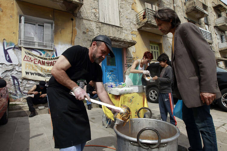 Constantinos Polychronopoulos, 47, an unemployed marketing specialist, distributes food portions at a soup kitchen for the poor in Athens, Greece, April 24, 2012 (CNS photo/John Kolesidis, Reuters).