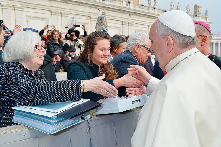 READING MATERIAL. Saint Mary’s College President Carol Ann Mooney, left, and Saint Mary’s student Kristen Millar, center. President Mooney is holding a binder with all the letters addressed to Pope Francis.