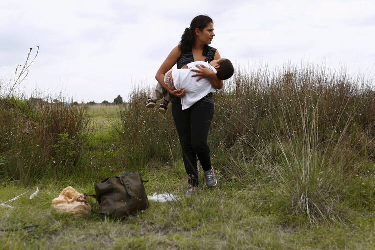 A Salvadoran immigrant en route to the United States carries her son while standing in vegetation June 1 to hide from organized crime bands in Huehuetoca, Mexico. (CNS photo/Edgard Garrido, Reuters)