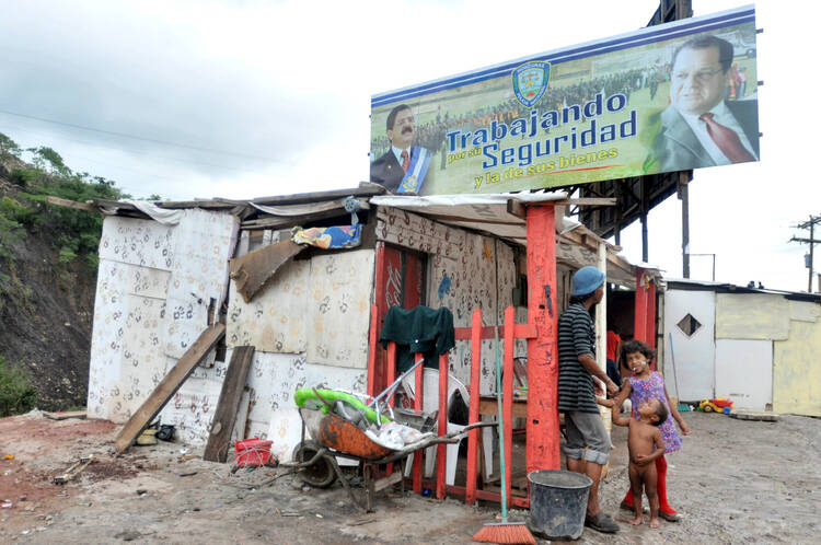 A family stands next to their makeshift home in Tegucigalpa, Honduras. (CNS photo/Gustavo Amador, EPA)