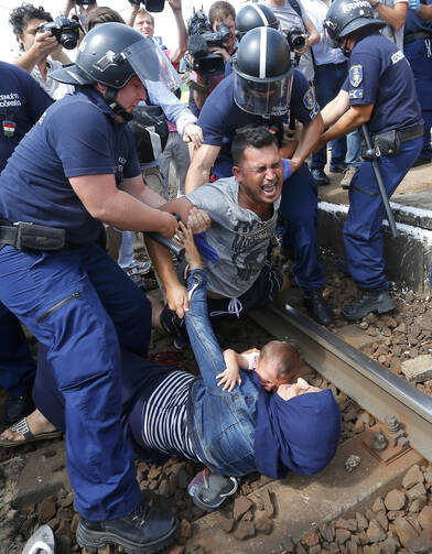 Hungarian policemen detain migrants on the tracks at a railway station in the town of Bicske, Hungary, Sept. 3. (CNS photo/Laszlo Balogh, Reuters)