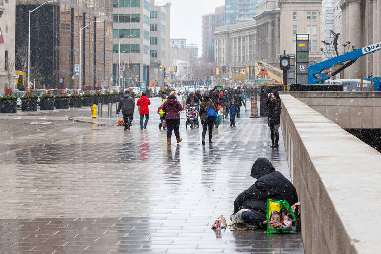 A man sits on a snowy street in Toronto, Ontario, Canada. In January, the city of Toronto began collecting data for the first time on deaths among its homeless population. (Photo via iStock)