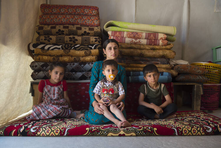 A young Yazidi woman sits with her three children inside a tent for displaced persons in northern Iraq on May 28, 2017. They fled the 2014 ISIS advance in which many Yazidis were killed and others, especially women and children, captured and trafficked by ISIS. (iStock/Joel Carillet)