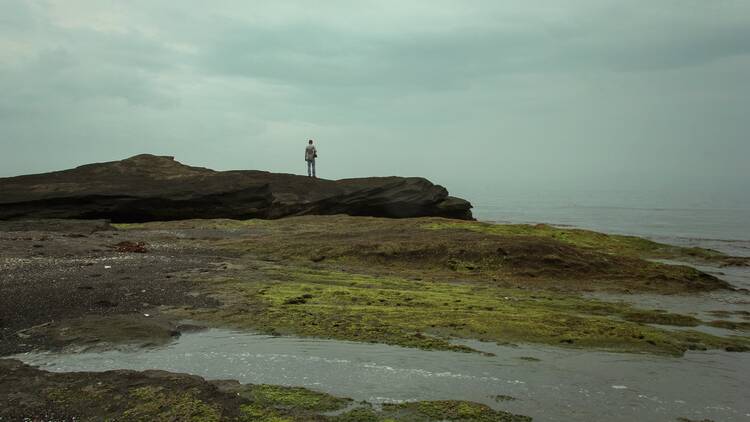 person standing on rock near body of water