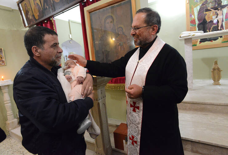 Father Souhail Khoury blesses a baby after Easter Monday Mass at St. Mary's Church in Iqrit, Israel, April 13. The residents were expelled by the Israeli army in 1948 and have never been able to permanently return to the village. (CNS photo/Debbie Hill)
