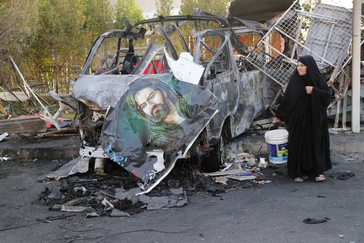 A woman walks past the site of a car bomb attack June 18 in Baghdad, Iraq. (CNS photo/Wissm al-Okili, Reuters)