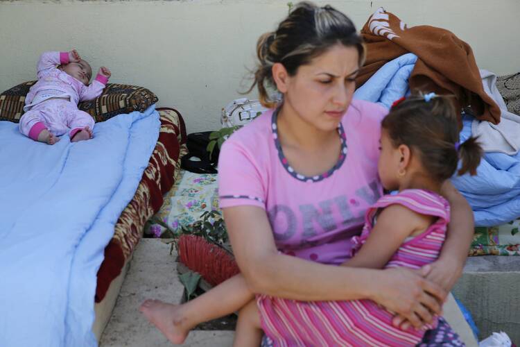 A Christian woman who fled from the violence in Mosul, Iraq, holds her daughter as her baby sleeps June 27 at a shelter in Irbil, Iraq. Chaldean Catholic Patriarch Louis Sako of Baghdad said the city of Mosul "is almost empty of Christians."