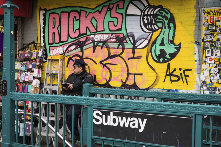 A police officer outside the subway entrance in Soho lower Manhattan on Canal street late in the day.