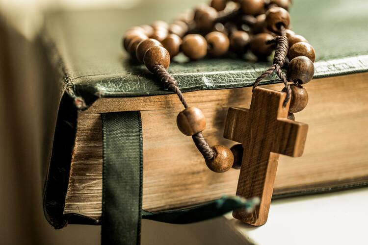 Brown prayer beads sitting on top of black book.
