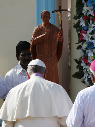 Pope Francis in front of stature of Joseph Vaz, a newly ordained saint, Jan 14 (CNS photo/Paul Haring).