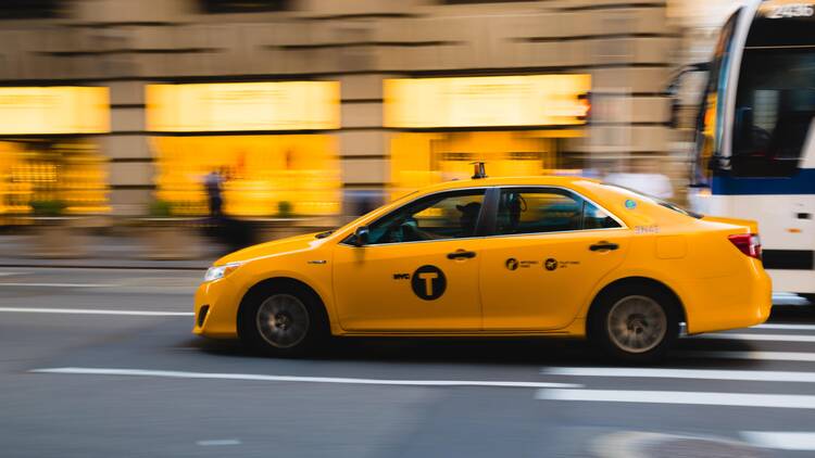 Stock image of a yellow taxi blurred as it speeds down the road.