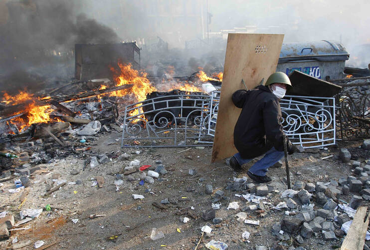 An anti-government protester takes cover behind a shield during a rally in Independence Square in central Kiev, Ukraine, Feb. 19. Ukraine's political crisis escalated sharply, with more than two dozen people killed and scores injured.