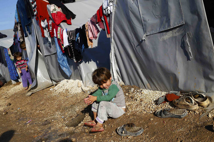 A Kurdish refugee child from the Syrian town of Kobani sits in front of a tent Oct. 18 in a camp on the Turkey-Syria border. (CNS photo/Kai Pfaffenbach, Reuters)