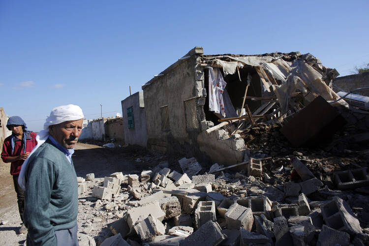 Local residents stand next to the debris of a house hit by a mortar shell from the Syrian side of the border in Alanyurt village near the Turkish-Syrian border Sept. 29. (CNS photo/Murad Sezer, Reuters)