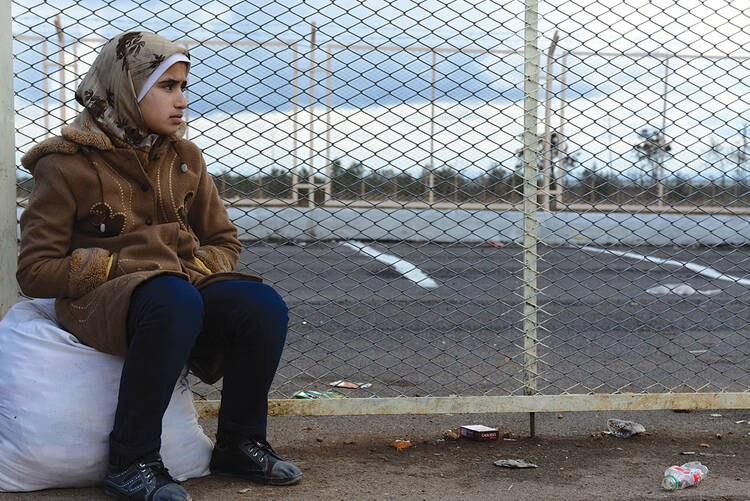 FAR FROM HOME. A Syrian girl in Turkey awaits a transport to a refugee camp.