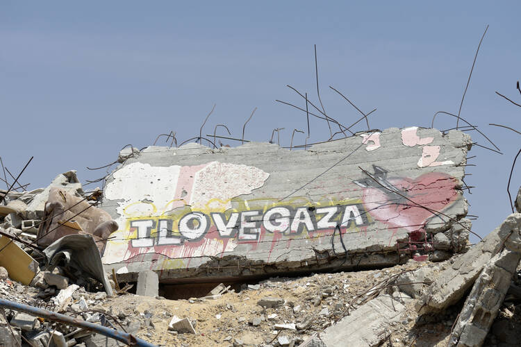 Neighborhood rubble with a message painted on a wall is seen in Gaza City June 6. Houses in the area were destroyed during the 2014 war between Israel and the Hamas government of Gaza. (CNS photo/Paul Jeffrey)