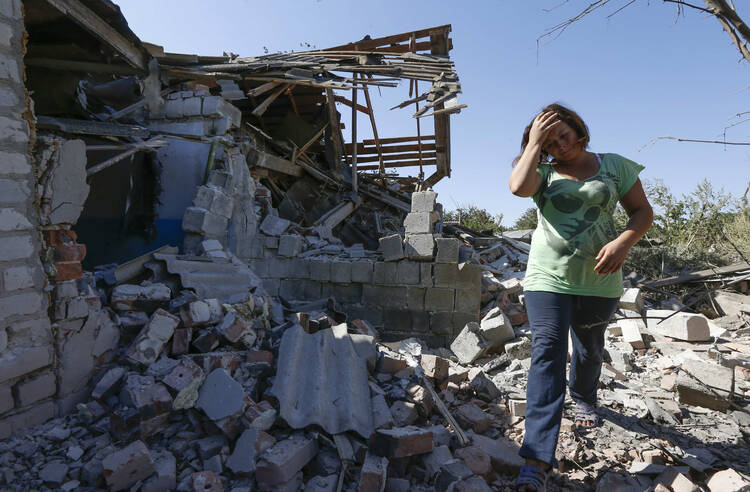 A woman walks at her destroyed house in the village of Kominternovo, Ukraine, near the southern coastal town of Mariupol in September. (CNS photo/Vasily Fedosenko, Reuters) 