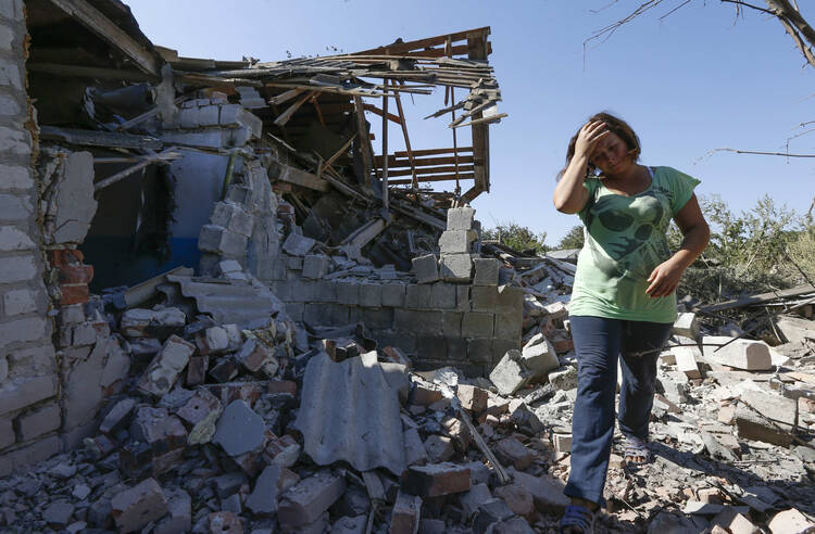 A woman walks at her destroyed house in the village of Kominternovo, Ukraine, near the southern coastal town of Mariupol in September. (CNS photo/Vasily Fedosenko, Reuters) 